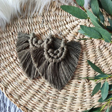 Load image into Gallery viewer, Moss coloured Boho Babe macramé earrings, eucalyptus leaves on the right side of the picture.

