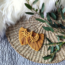 Load image into Gallery viewer, Mustard coloured Boho Babe macramé earrings, eucalyptus leaves on the right side of the picture.
