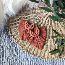 Load image into Gallery viewer, Terracotta coloured Boho Babe macramé earrings, eucalyptus leaves on the right side of the picture.
