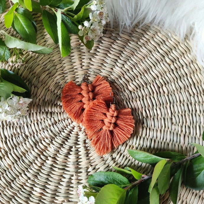 The Feather Babies macramé earrings in colour Brick, green leaves and flowers on the sides.