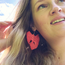 Load image into Gallery viewer, A model wearing The Feather Babies macramé earrings in colour Coral, blue sky and white clouds on the background.
