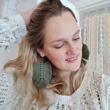 Load image into Gallery viewer, A model in a white shirt wearing The Feather Girls macramé earrings in colour Moss.
