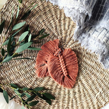 Load image into Gallery viewer, The Feather Girls macramé earrings in colour Terracotta, green eucalyptus leaves on the left side of the picture.
