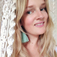 Load image into Gallery viewer, A model wearing macramé tassel earrings Pillow Talk in a shade Mint Green, white macramé curtains on the sides,
